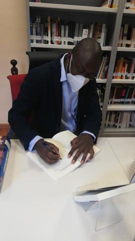 Patrick Kabou firma un ejemplar de 'Guerra y Paz en África' en la Mediateca Casa África